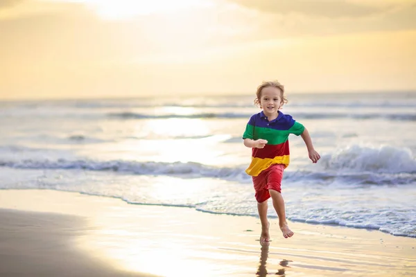 Bambino che gioca sulla spiaggia dell'oceano. Ragazzo al tramonto mare . — Foto Stock