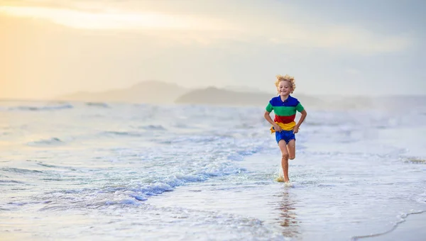 海のビーチで遊ぶ子。サンセットの海を子供します。. — ストック写真