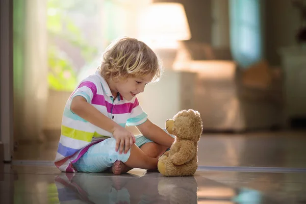 Ребенок играет с плюшевым мишкой. Ребенок и игрушка дома — стоковое фото
