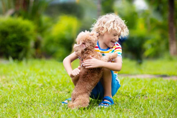 Les enfants jouent avec le chiot. Enfants et chien dans le jardin . — Photo