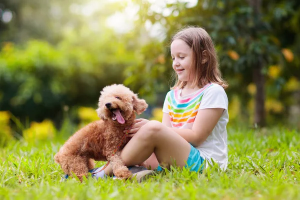 Kinderen spelen met puppy. Kinderen en honden in de tuin. — Stockfoto