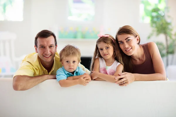 Familia feliz en casa. Padres e hijos en el sofá . — Foto de Stock