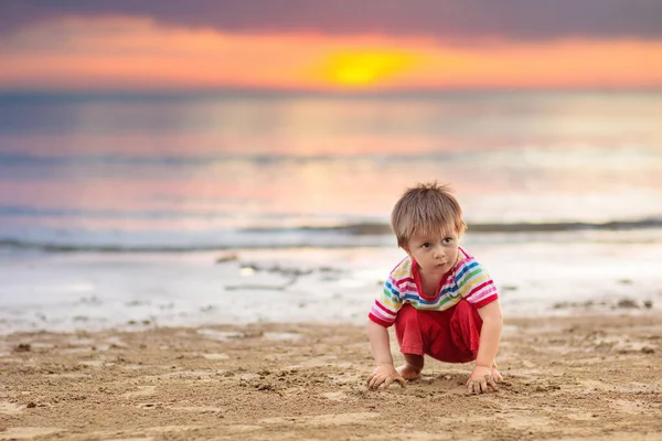 Okyanus plaj üzerinde oynayan çocuk. Gün batımı denizde evlat. — Stok fotoğraf