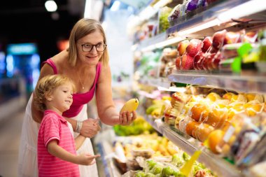 Mother and child buying fruit in supermarket.