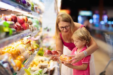 Mother and child buying fruit in supermarket.