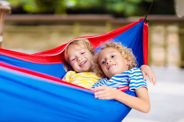 Jongen in hangmat. Kinderen spelen in de zomertuin. — Stockfoto
