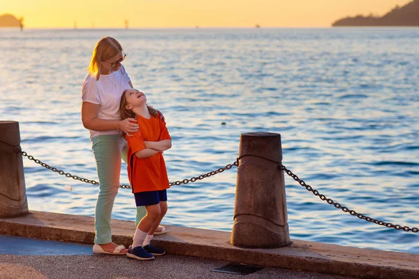 Moeder en kind aan zee bij zonsondergang. — Stockfoto