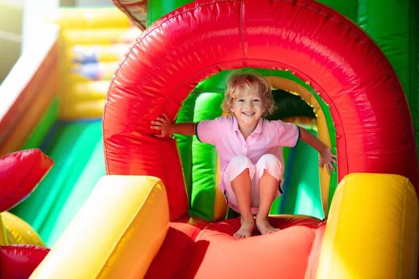 子供はカラフルな遊び場トランポリンでジャンプします 子供たちは幼稚園の誕生日パーティーでインフレータブルバウンス城にジャンプします 夏に屋外で遊ぶ男の子 — ストック写真