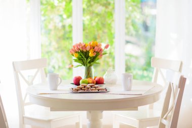 Homemade cookies on breakfast table in white sunny dining room or kitchen. Fruit and pastry for tea party. Fresh baked lemon cookie pile.