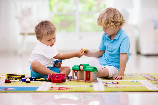 Little boys fighting over toy car. Boy playing toy cars on play mat. Young kid with vehicle and transport toys on carpet. City street map rug. Child driving car to parking garage. Kids learn to share.