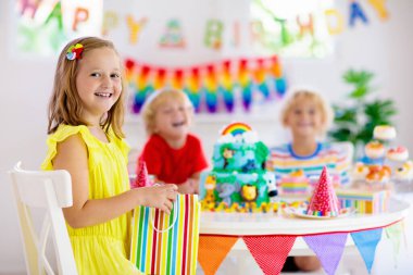 Çocukların doğum günü partisi. Çocuk pastaya mum üflüyor ve orman temalı kutlamalarda hediyeler açıyor. Çocuk etkinliği için pasta tatlısı. Oğlan ve kız doğum gününü kutluyor. Çocuklar için hediyeler ve tatlılar.