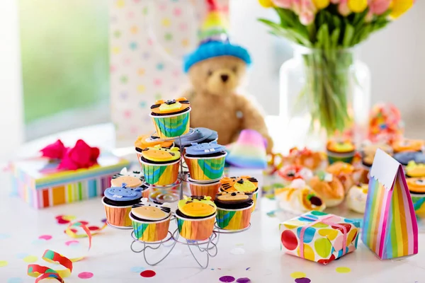 Cupcakes for kids birthday celebration. Jungle animals theme children party. Decorated room for boy or girl kid birthday. Table setting with presents, gift boxes, confetti and sweets. Pastry for child