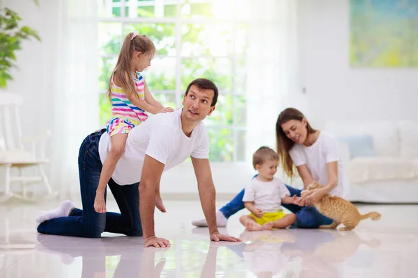 有孩子在家里的快乐的年轻家庭 女儿和儿子在客厅的地板上玩耍 小男孩和小女孩抱着宠物猫 父母和孩子一起玩 — 图库照片