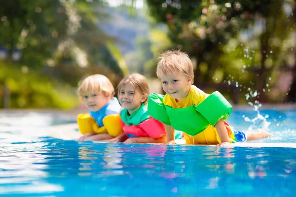 孩子们在热带度假胜地的室外游泳池里玩耍 给小孩游泳助教 宝宝学习潜水 一群在水里玩耍的孩子 色彩艳丽的救生衣海滩和夏天的乐趣 — 图库照片