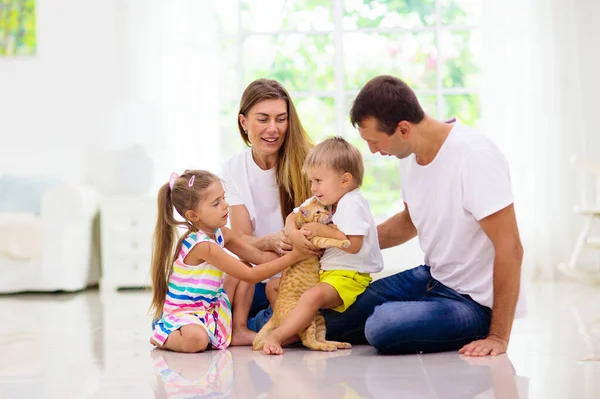 有孩子在家里的快乐的年轻家庭 女儿和儿子在客厅的地板上玩耍 小男孩和小女孩抱着宠物猫 父母和孩子一起玩 — 图库照片