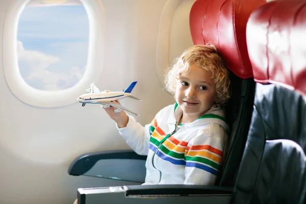 飛行機の子供 子供の航空機の窓の席に座っている 子供のための飛行エンターテイメント 若い子供たちと一緒に旅行 子供たちは飛んで旅行します 家族の夏休み 飛行機の中でおもちゃを持つ男の子 — ストック写真