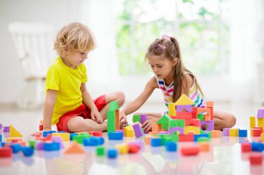 Çocuklar renkli bloklarla oynarlar. Küçük çocuk ve kız evde ya da kreşte kule inşa ederler. Küçük çocuk için eğitici bir oyuncak. Bebek ya da bebek için yaratıcı bir oyun. Anaokulu oyun odasında karışıklık..