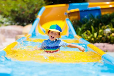 Su parkında su kayağı yapan çocuklar. Çocuklar yaz tatilinde tropik tatil köylerinde su kaydırağında eğleniyorlar. Islak çocuk ve bebek parkı olan eğlence parkı.