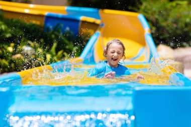Su parkında su kayağı yapan çocuklar. Çocuklar yaz tatilinde tropik tatil köylerinde su kaydırağında eğleniyorlar. Islak çocuk ve bebek parkı olan eğlence parkı.