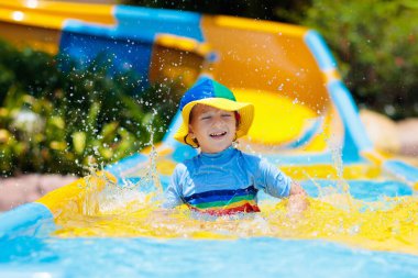 Su parkında su kayağı yapan çocuklar. Çocuklar yaz tatilinde tropik tatil köylerinde su kaydırağında eğleniyorlar. Islak çocuk ve bebek parkı olan eğlence parkı.