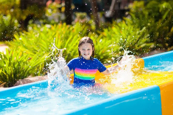 アクアパークのウォータースライダーの子供たち 熱帯のリゾートで家族の夏休みにウォータースライドで楽しんでいる子供たち 子供と赤ちゃんのためのぬれた遊び場を持つ遊園地 — ストック写真