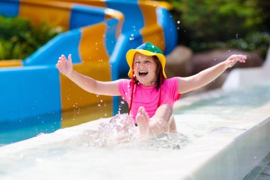 Su parkında su kayağı yapan çocuklar. Çocuklar yaz tatilinde tropik tatil köylerinde su kaydırağında eğleniyorlar. Islak çocuk ve bebek parkı olan eğlence parkı.