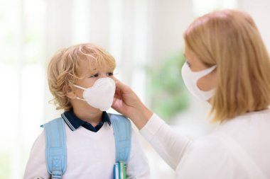 Yüzü maskeli çocuklar okula ya da anaokuluna gidiyor. Anne ve çocuk koronavirüs ve grip salgını sırasında yüz maskesi takıyor. Virüs ve hastalık koruması, kalabalık yerlerde el dezenfektanı..