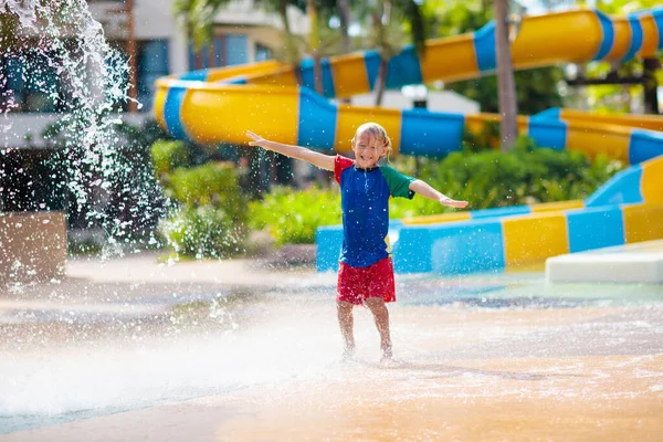 ウォーターパークでチップバケツの下で遊んでいる子供 子供たちはスプラッシュダンプバケツで遊ぶ 暑い夏の日に遊園地で家族の楽しみ 子供のための太陽の保護 子供のためのウォータースライド — ストック写真