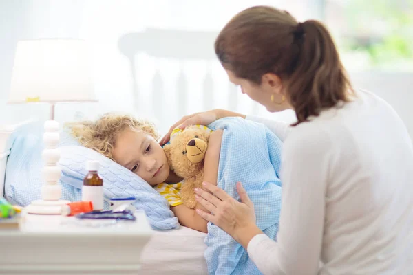 生病的小男孩哮喘药物 孩子生病的母亲躺在床上 有卧床吸入器治疗咳嗽的病童 流感季节 年幼病人的家长在卧室或病房 — 图库照片