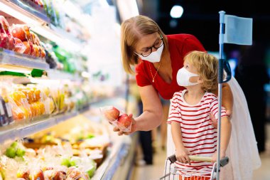 Shopping with kids. Mother and child buying fruit in supermarket. Mom and little boy buy fresh mango in grocery store. Family in shop. Parent and children in a mall choosing vegetables. Healthy food.