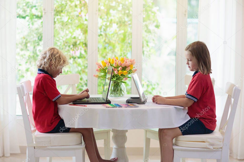 Homeschooling. Kids learning from home. Remote school, online education for young children during quarantine. Kid with laptop and tablet computer. Little girl and boy study.