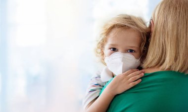 Alışveriş merkezinde ya da havaalanında maskeli çocuklar. Anne ve çocuk koronavirüs ve grip salgını sırasında yüz maskesi takıyor. Virüs ve hastalık koruması, kalabalık yerlerde el dezenfektanı..