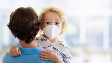 Alışveriş merkezinde ya da havaalanında maskeli çocuklar. Baba ve çocuk koronavirüs ve grip salgını sırasında yüz maskesi takıyor. Virüs ve hastalık koruması, kalabalık yerlerde el dezenfektanı..