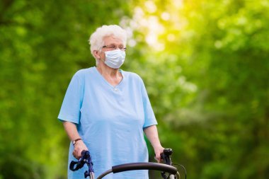 Corona virüsü ve grip salgını sırasında yüz maskesi takan yaşlı bir kadın. Hastalık ve hastalık koruması. Koronavirüsü önlemek için cerrahi maskeler. Hasta, yaşlı bir hasta öksürüyor. Hasta kişi..