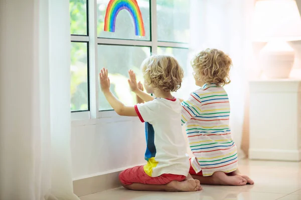 コロナウイルスの隔離 家にいて 子供たちは窓に座っている 希望の虹のサインを描く子供たち コロナウイルスの封鎖中の少年少女 子供とペット 屋内で家族の隔離 病気予防 — ストック写真