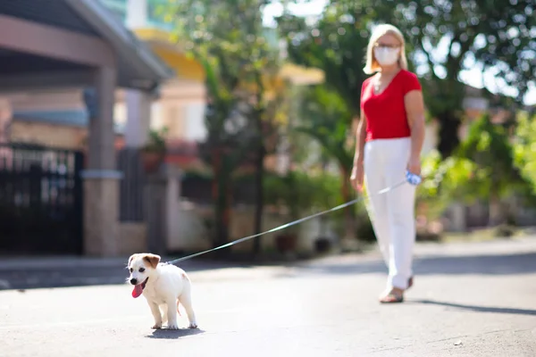 Family walking dog during virus outbreak. Woman and child wearing face mask in coronavirus lockdown and quarantine. Home animal and pet. Mother and child with puppy in pandemic or air pollution.