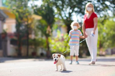 Virüs salgını sırasında aileyi gezdiren köpek. Coronavirus tecrit ve karantinasında yüz maskesi takan kadın ve çocuk. Ev hayvanı ve evcil hayvan. Anne ve çocuğu salgın ya da hava kirliliği içinde..