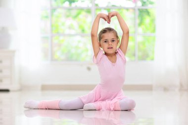 Evde bale eğitimi. Uzaktan öğrenme. Dans sınıfındaki küçük balerin. Tutu ve tayt içinde dans etmeyi öğrenen tatlı bir kız. Çocuklar için klasik koreografi. Çocuk dansçısı egzersiz yapıyor. Çevrimiçi bale kursu.