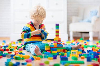 Çocuk renkli oyuncak bloklarıyla oynuyor. Küçük çocuk evde ya da kreşte kule inşa ediyor. Küçük çocuklar için eğitici oyuncaklar. Bebek ya da bebek için inşaat bloğu. Anaokulundaki oyun odasında karışıklık..