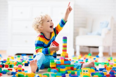 Çocuk renkli oyuncak bloklarıyla oynuyor. Küçük çocuk evde ya da kreşte kule inşa ediyor. Küçük çocuklar için eğitici oyuncaklar. Bebek ya da bebek için inşaat bloğu. Anaokulundaki oyun odasında karışıklık..
