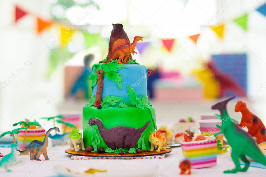 Kids birthday party. Dinosaur theme layer cake. Children event. Decoration for dinosaurs themed celebration.