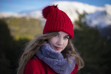 Kırmızı giyinmiş, kırmızı şapkalı bir kadın oturuyor. 