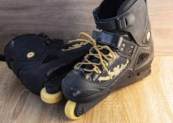 photographs of black inline skates with golden laces on wooden floor