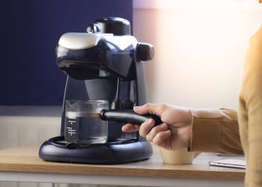Evdeki kahve makinesinde kahve hazırlayan adam.