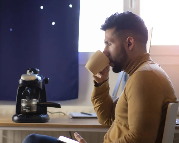 man in sweater drinking coffee at home