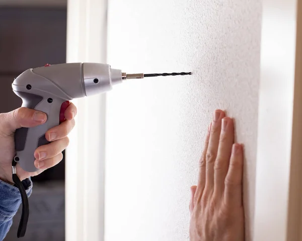 man with drill on the wall making hole