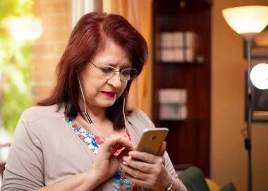 Son sınıf öğrencisi kadın cep telefonu ve kulaklıklarıyla yeni teknoloji aramaları yapıyor.