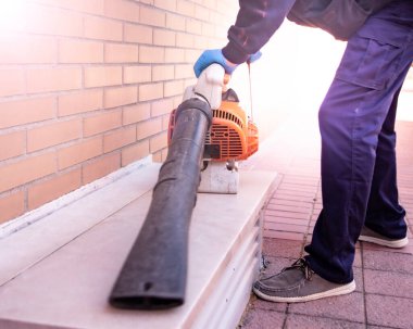 Sokakta çalışan bir işçi Yaprak üfleyicisi olan bir adam