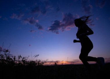 Gün batımında koşan atletler. günbatımı bulutları