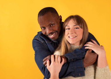 Birbirlerine sarılıp gülümseyen çok ırklı bir çift.